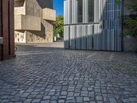 cobblestone driveway surrounded by modern buildings on sunny day with sun reflecting onto the windows