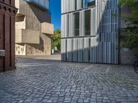 cobblestone driveway surrounded by modern buildings on sunny day with sun reflecting onto the windows