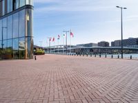 a red brick sidewalk next to water and a walkway leading up to a glass building