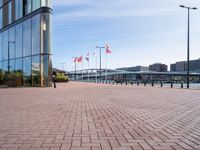 a red brick sidewalk next to water and a walkway leading up to a glass building