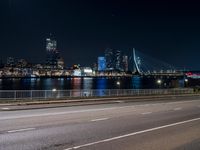 an empty freeway with the city skyline in the distance at night time in this image