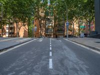 the street is empty except for a one way road to be crossed by buildings and trees