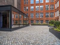 an empty parking lot with plants in the ground and on the side of the building, there is an enclosed area and windows