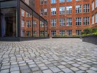 an empty parking lot with plants in the ground and on the side of the building, there is an enclosed area and windows