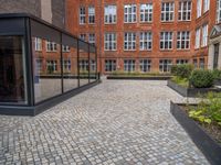 an empty parking lot with plants in the ground and on the side of the building, there is an enclosed area and windows