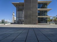 a long concrete building on top of a sidewalk next to a big metal tower that has a bench underneath it