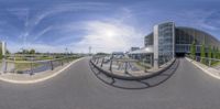 a view through a fish eye lens of an outside area that includes an open air walkway, and building next to a bike path