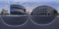 a wide angle view of an intersection in a city with buildings on both sides and sky in the background