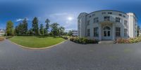 a view looking down at a driveway in front of a large white mansion or home