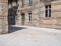 a person riding a skateboard on a brick road next to a building with windows