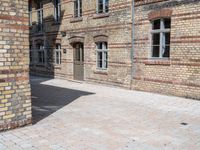 a person riding a skateboard on a brick road next to a building with windows