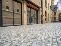 a street that has a large brick road and tall buildings in it with glass doors