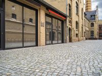 a street that has a large brick road and tall buildings in it with glass doors