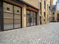 a street that has a large brick road and tall buildings in it with glass doors