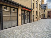 a street that has a large brick road and tall buildings in it with glass doors