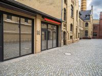 a street that has a large brick road and tall buildings in it with glass doors