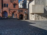 cobblestone driveway surrounded by modern buildings on sunny day with sun reflecting onto the windows