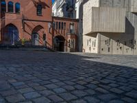 cobblestone driveway surrounded by modern buildings on sunny day with sun reflecting onto the windows