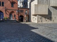 cobblestone driveway surrounded by modern buildings on sunny day with sun reflecting onto the windows