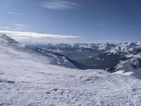 man standing in the snow with skis looking over mountain ranges from top of mountain