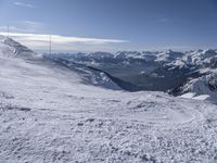 man standing in the snow with skis looking over mountain ranges from top of mountain