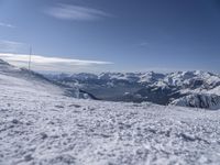 man standing in the snow with skis looking over mountain ranges from top of mountain