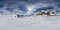 there is snow covering the ground, and there are mountain tops in the background under a cloud