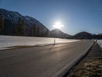 a sun setting over a mountain valley with no cars in the distance on a cold, winter day