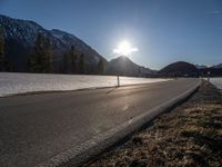 a sun setting over a mountain valley with no cars in the distance on a cold, winter day