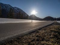 a sun setting over a mountain valley with no cars in the distance on a cold, winter day