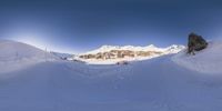 snow covered ground with a snowboarder going down the slope and a mountain in the background