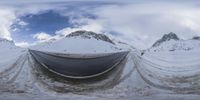 snow covers are all over the mountain on the slope, in the foreground is the road