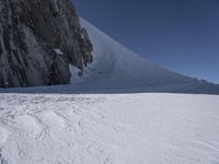 a person is skiing in the snow on a steep hill with a huge rock formation in the back