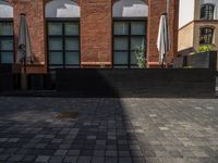 a sidewalk with chairs next to the brick building on the side, some have stairs and some buildings in the background