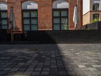 a sidewalk with chairs next to the brick building on the side, some have stairs and some buildings in the background
