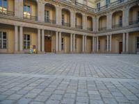 a courtyard with a building on the other side and a large white building with many windows