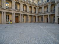 a courtyard with a building on the other side and a large white building with many windows