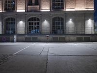 a fire hydrant is seen by an old brick building at night, with the lights turned on