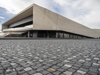 a small child walking towards a large building with a ramp on top of it on a cobblestone street