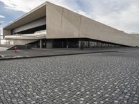 a small child walking towards a large building with a ramp on top of it on a cobblestone street