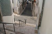 an alleyway with some cars coming up the steps and an empty street with a woman walking along