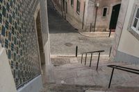 an alleyway with some cars coming up the steps and an empty street with a woman walking along