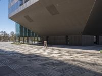 a large open courtyard in front of modern building in public area area with glass windows and floor tiles