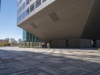 a large open courtyard in front of modern building in public area area with glass windows and floor tiles