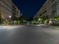 an empty street at night with the light turned on and cars parked on it in the distance