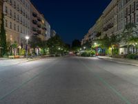 an empty street at night with the light turned on and cars parked on it in the distance