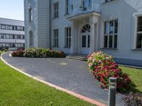 a nice building in front of a nice green grass lawn with some plants and flowers