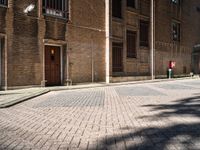 a fire hydrant sitting in the middle of an alley lined with tall brick buildings