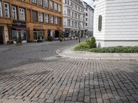brick street in europe with an intersection in the middle of it, and shops along it