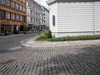 brick street in europe with an intersection in the middle of it, and shops along it